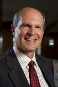 A person in a suit and tie smilingDescription automatically generated